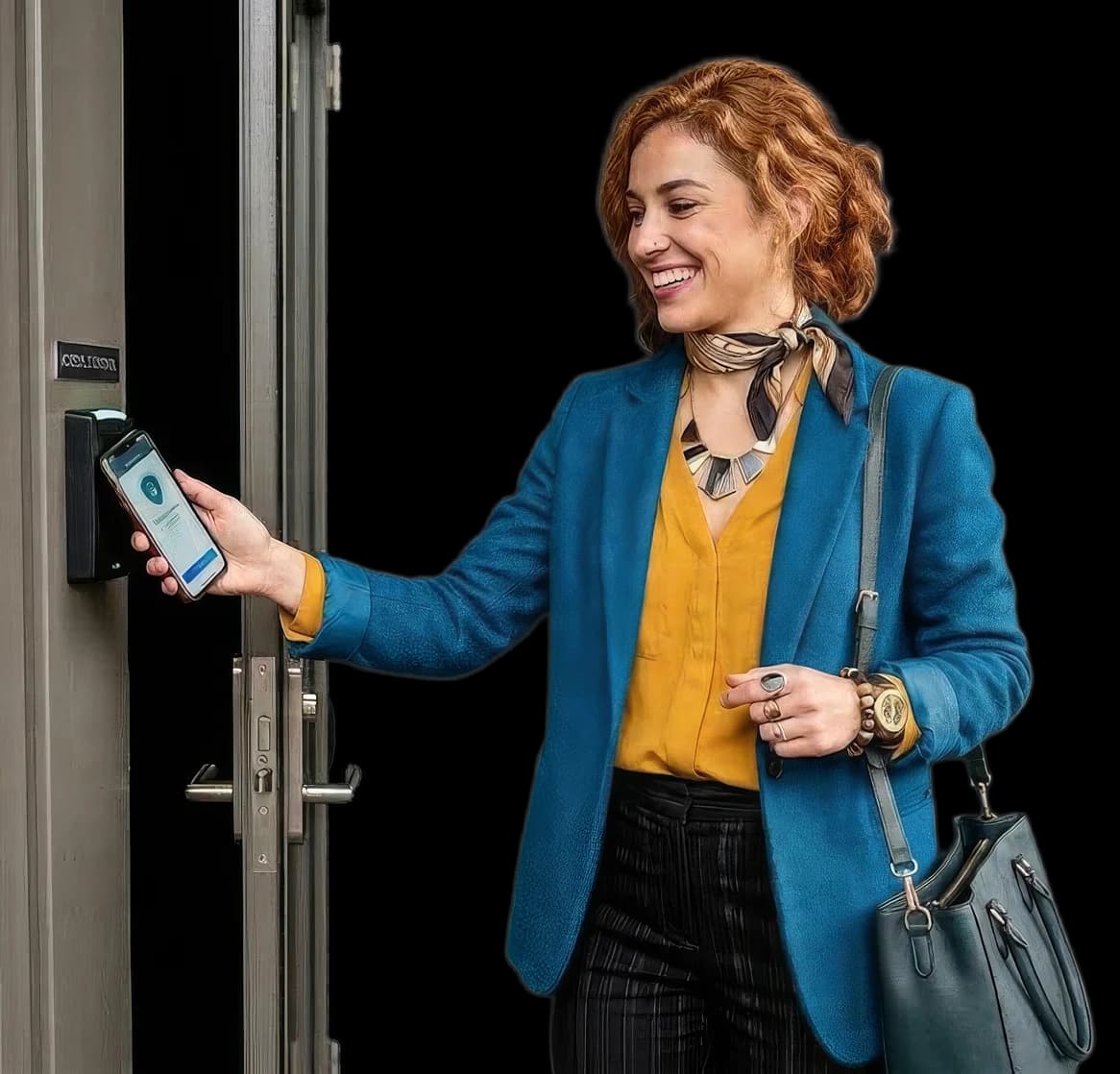 Nasmiješena žena u plavom sakou prislanja telefon s karticom za pristup na zidni NFC čitač pokraj vrata.